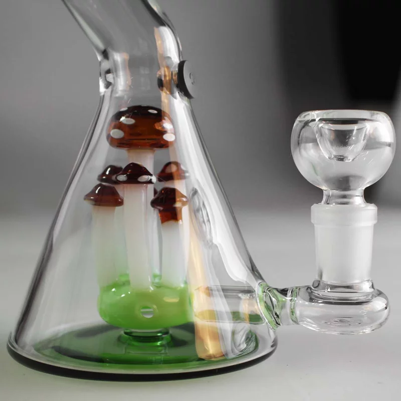 Detailbild des Korpus einer Beaker-Bong, grüner Boden, darüber transparentes Glas, im Inneren mehrere Fliegenpilze als Perkolator, rechts geht der Kräuterkopf ab