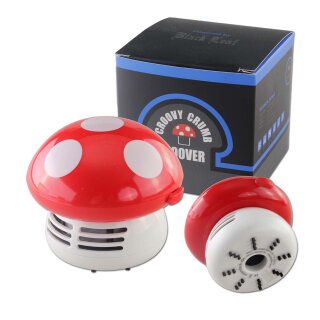Pilzförmiger Tischstaubsauger in Rot mit weißen Punkten, bestehend aus Kunststoff. Der Staubsauger steht neben seiner Verpackung mit blau-schwarzem Design und Logo vorne.