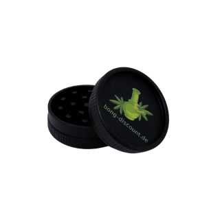 Schwarzer geöffneter Grinder, zweiteilig, mit grünem bong-discount Logo, Deckel lehnt am Unterteil, die Blockzähne im Inneren sind zu erkennen