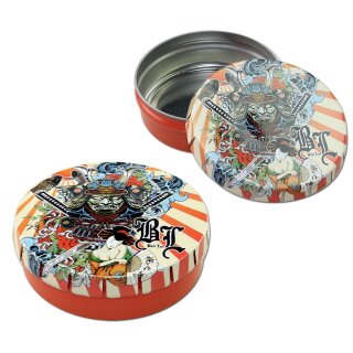 Dose aus Metall mit abnehmbarem Deckel, mehrfarbig bedruckt mit Samurai-Motiv, roten Seitenwänden und silbernem Innenraum. Deckel zeigt detailliertes Design, liegt neben der Dose.