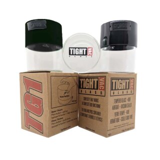 Zwei Glasbehälter mit schwarzen Kunststoffdeckeln und ein weiterer ohne, liegend, mit TightVac Aufdruck auf dem Boden. Sie alle stehen auf zwei braunen Kartonverpackungen mit Produktinformationen.